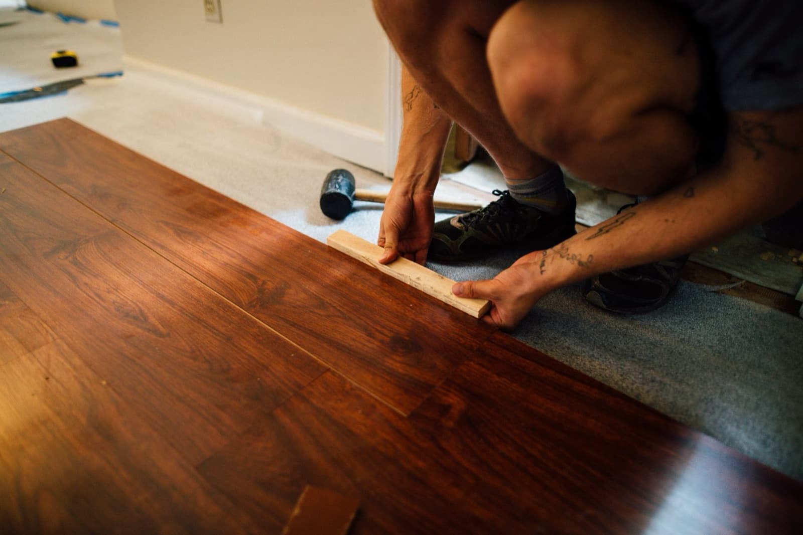 Installer laying plank flooring in a renovated room