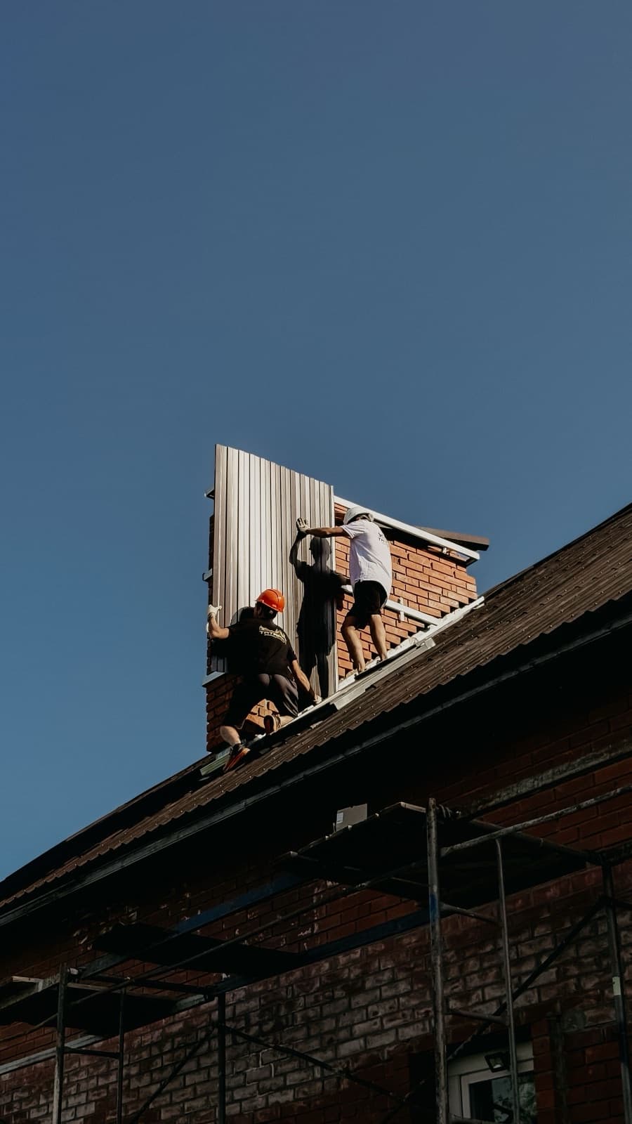 Workers installing metal roof panels