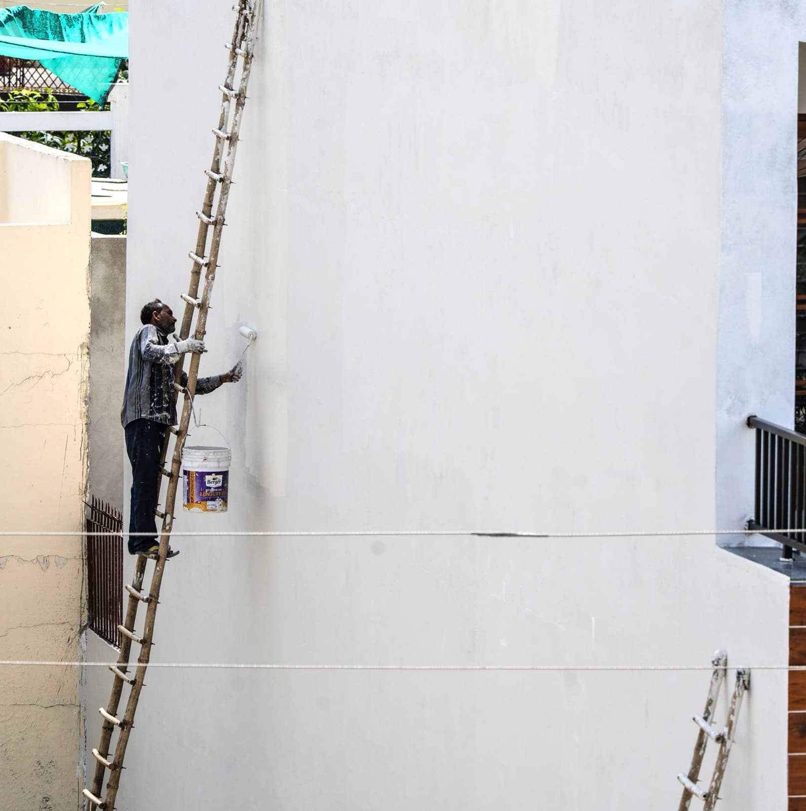 Painter on a ladder painting an exterior wall