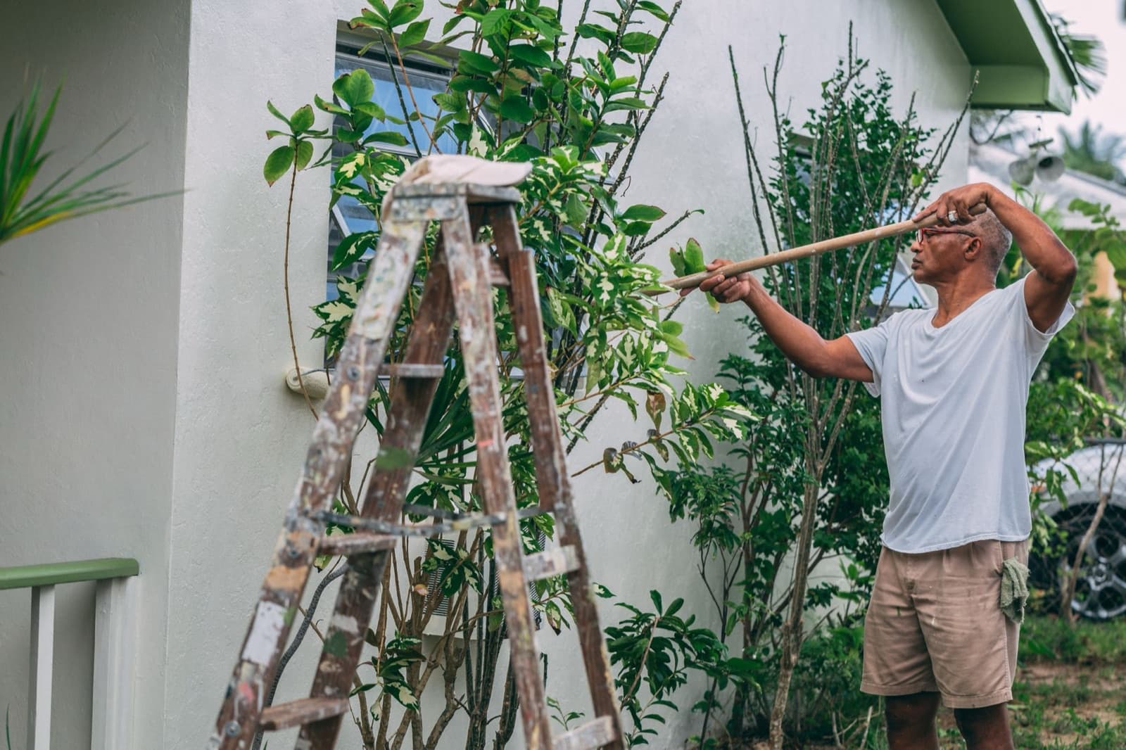 Painter applying exterior paint to a house wall with a roller
