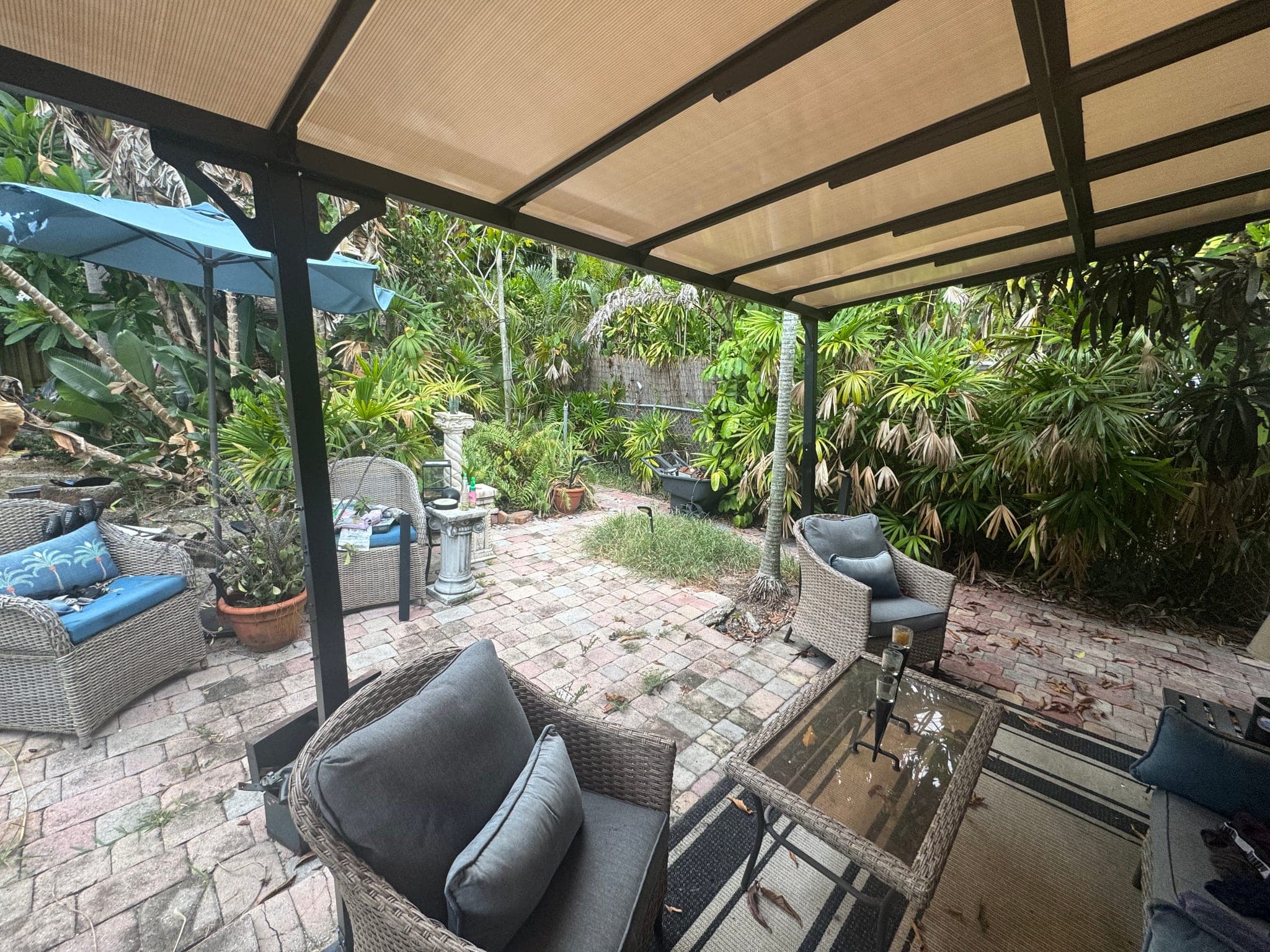 Covered patio with worn furniture and a dirt yard beyond, before