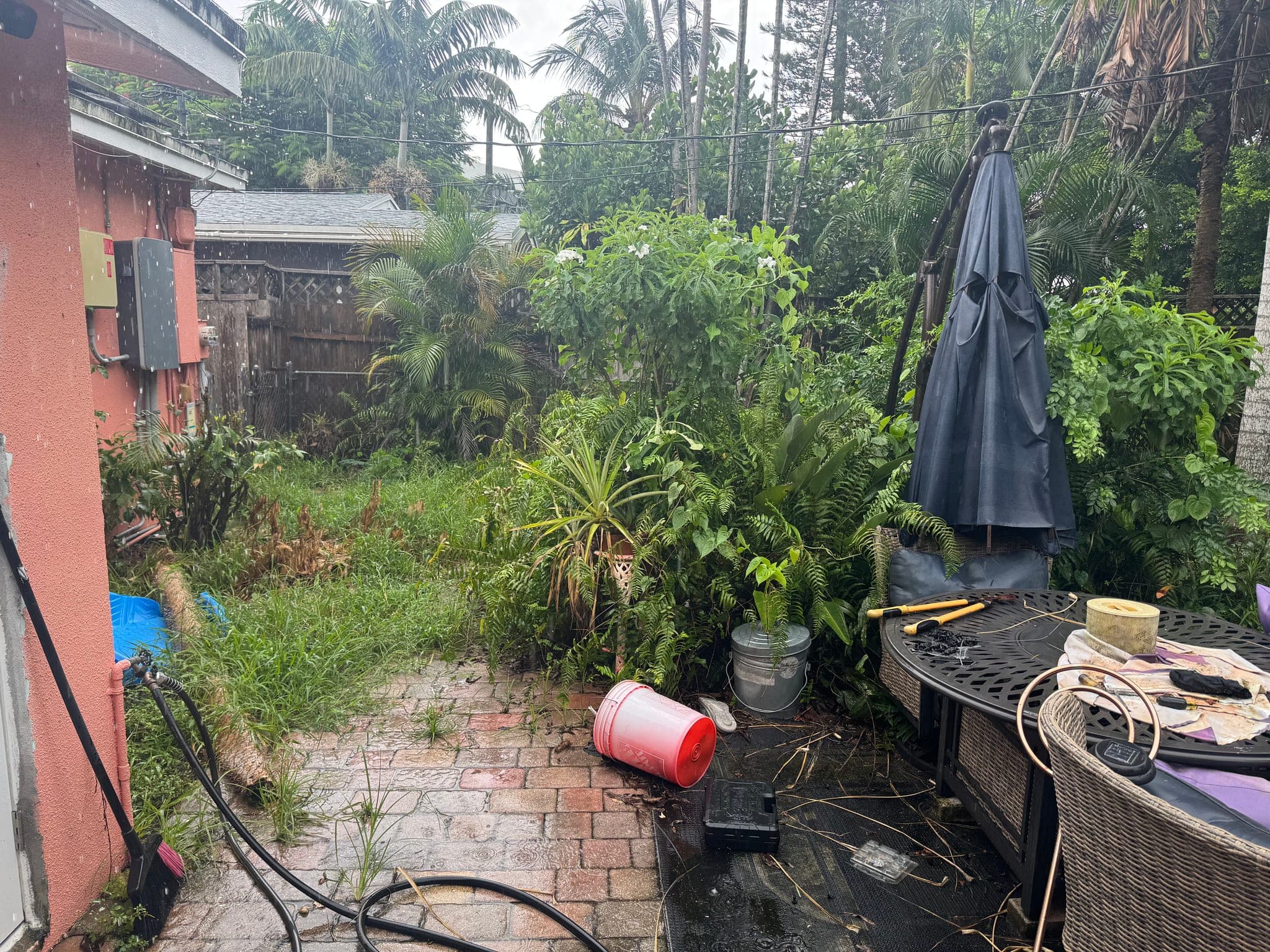 Patio furniture and closed umbrellas on a bare yard, before