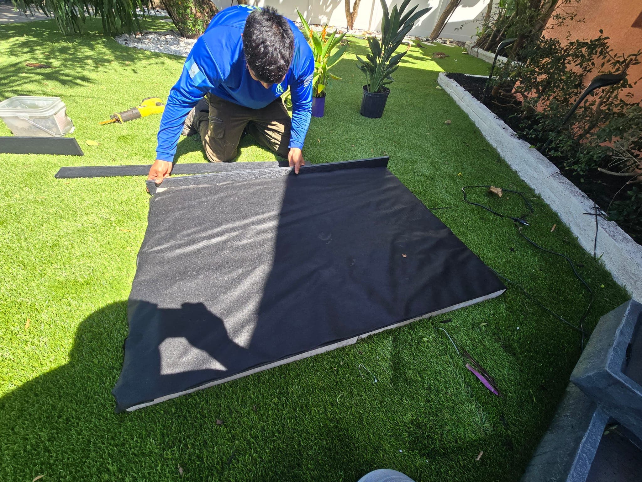 Crew member laying geotextile fabric before the artificial turf