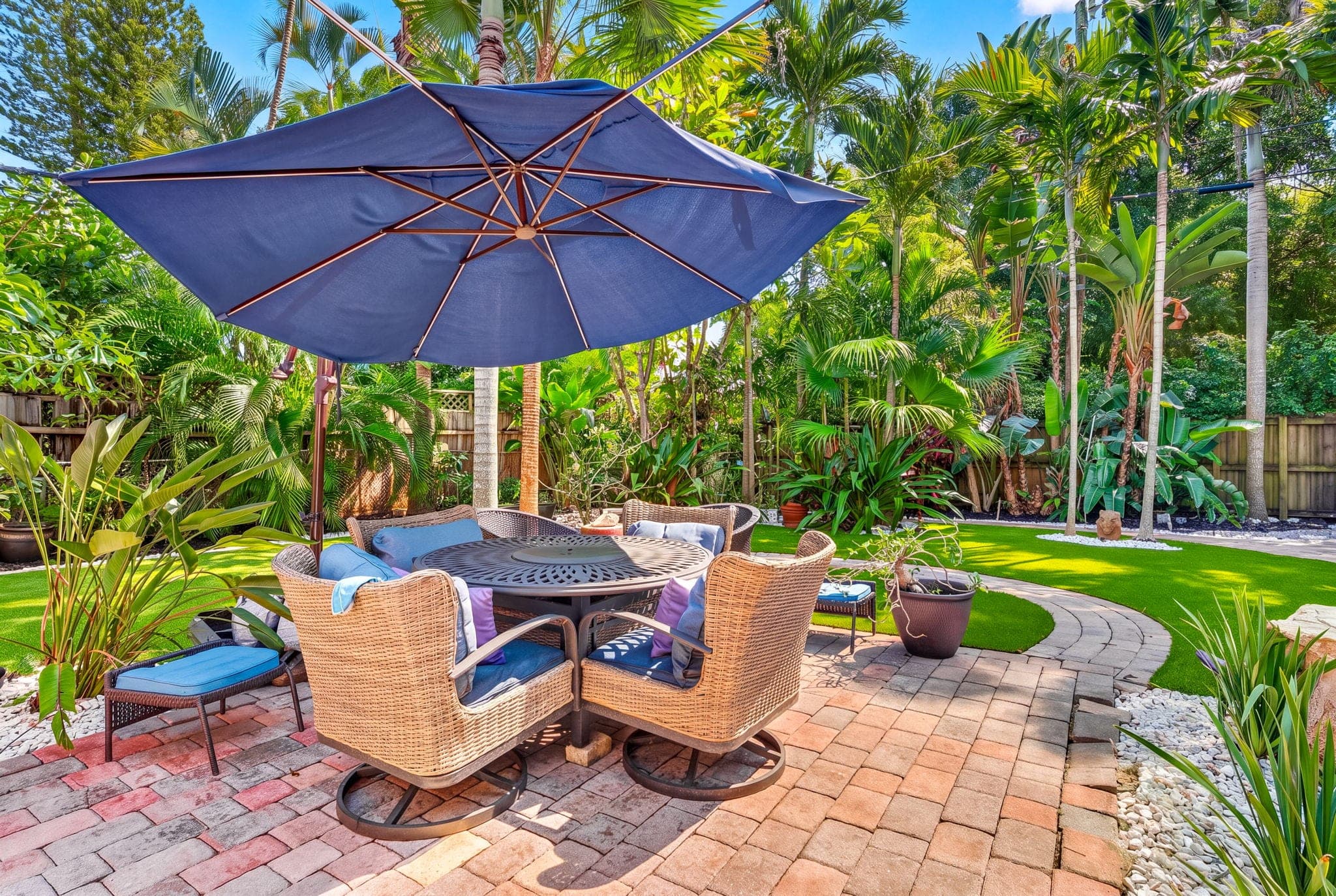 Covered patio seating under a blue umbrella on new pavers