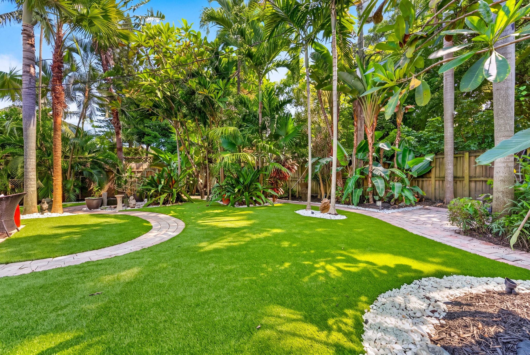 Curved paver path through the turf toward the back fence
