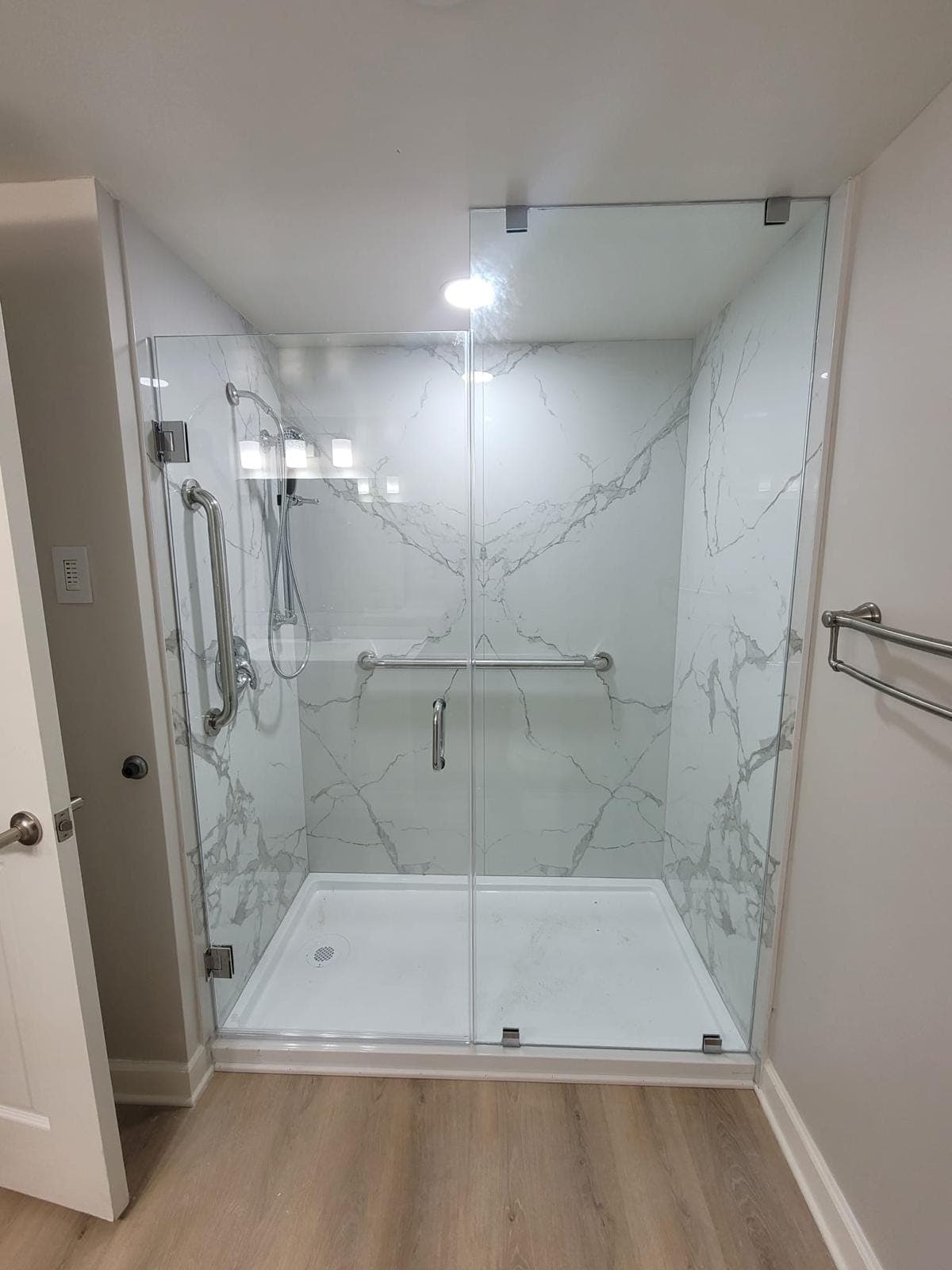 Frameless glass shower with chrome grab bars