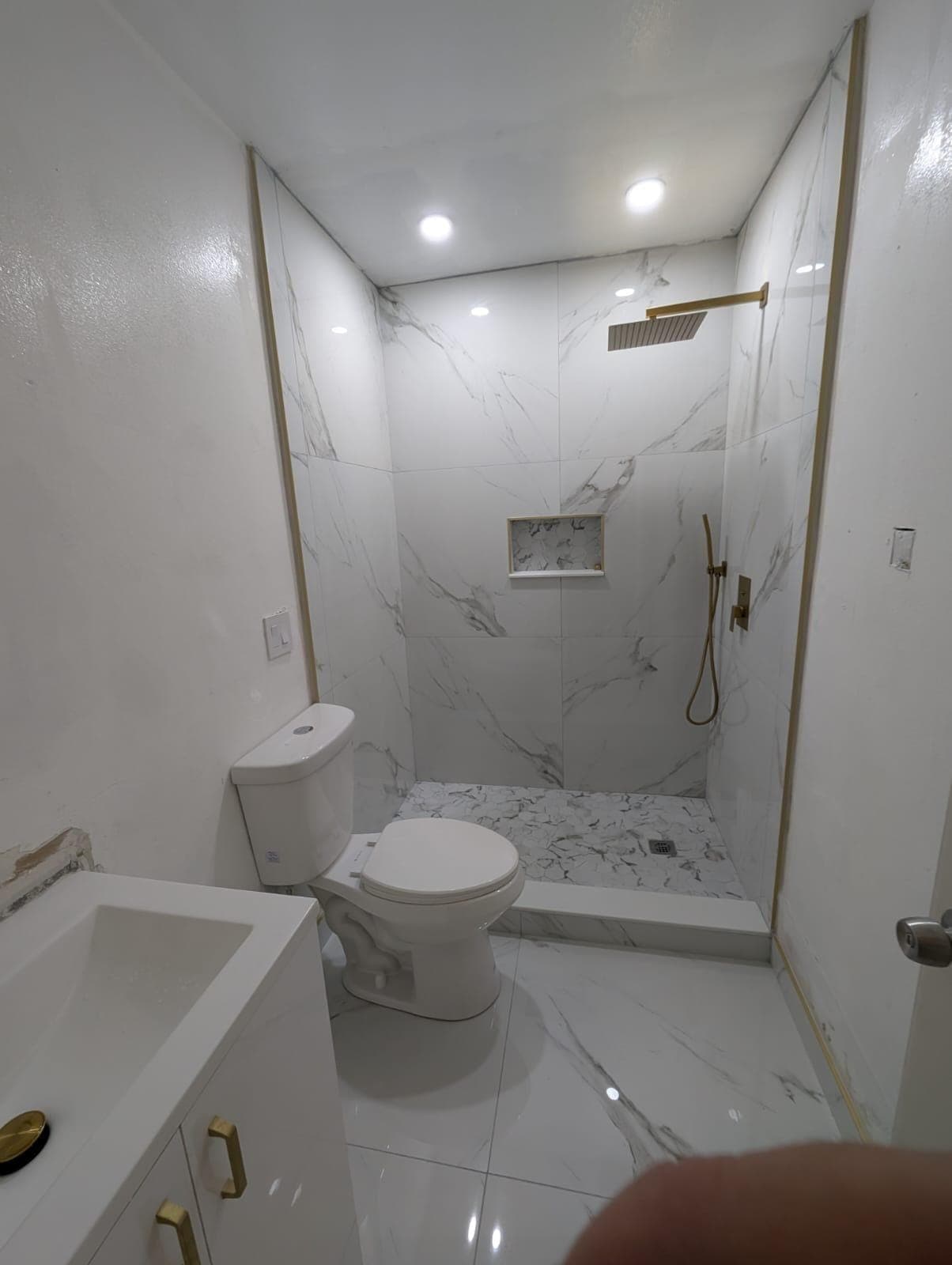 Marble-look shower with gold rain head and recessed niche
