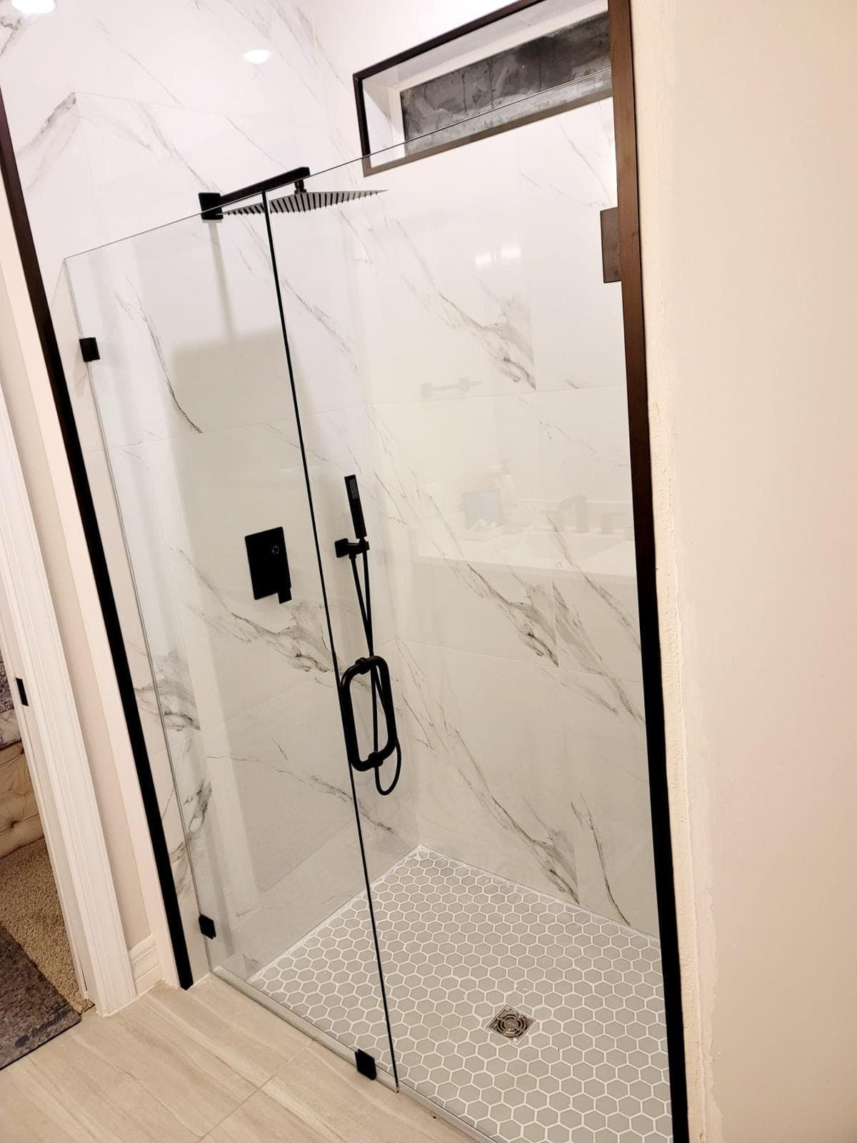 Frameless black-framed shower door on marble-look tile