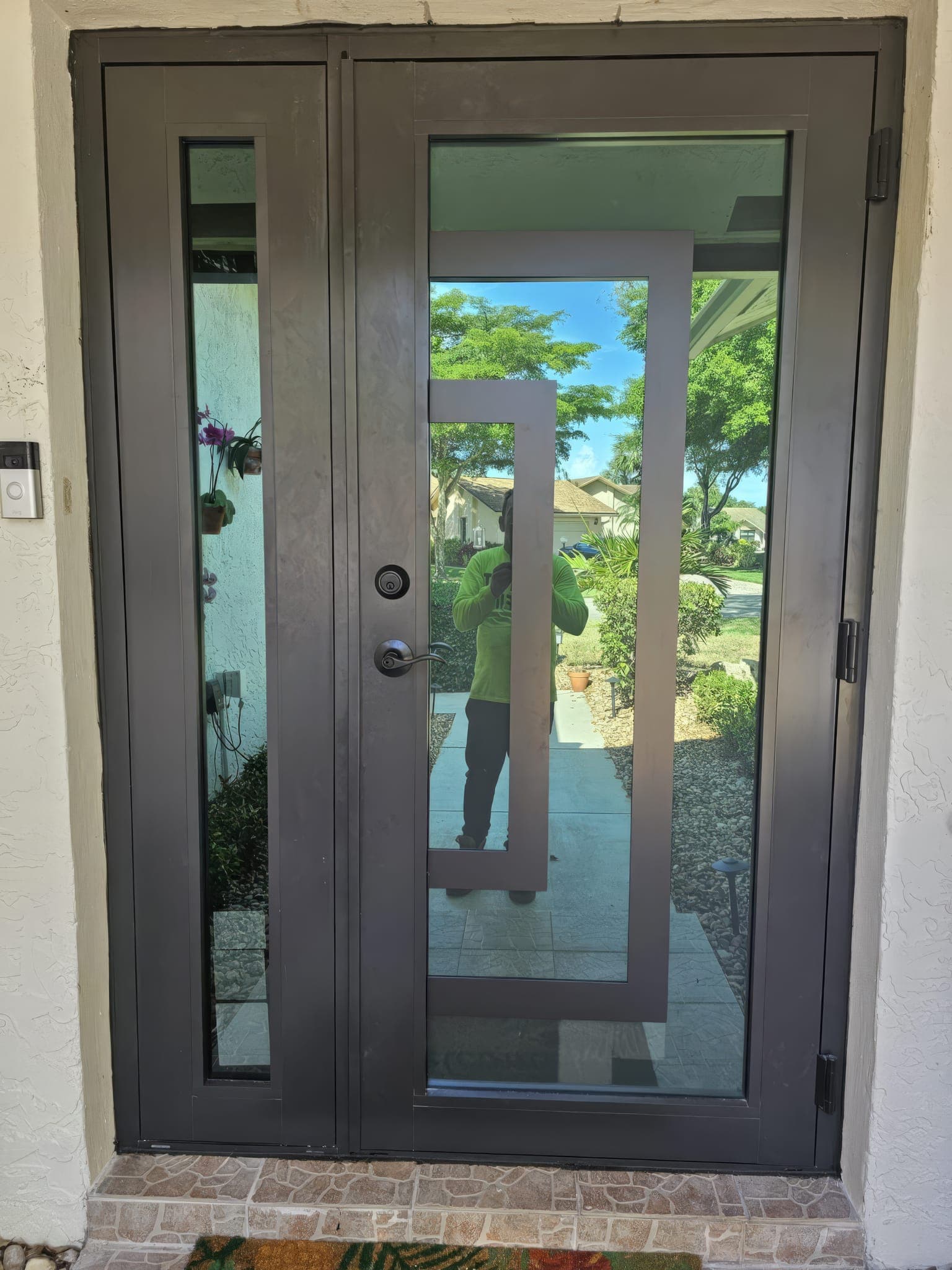 Front entry double door seen from the walkway, bronze frame and frosted glass