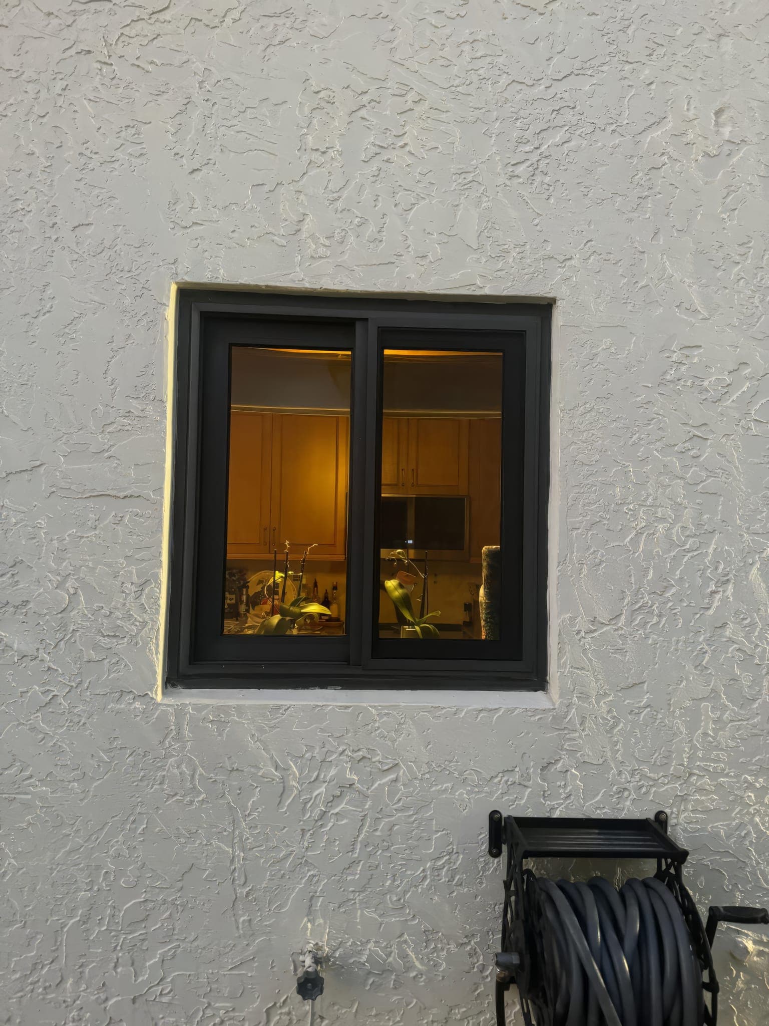 Impact slider window installed in the stucco wall beside the patio