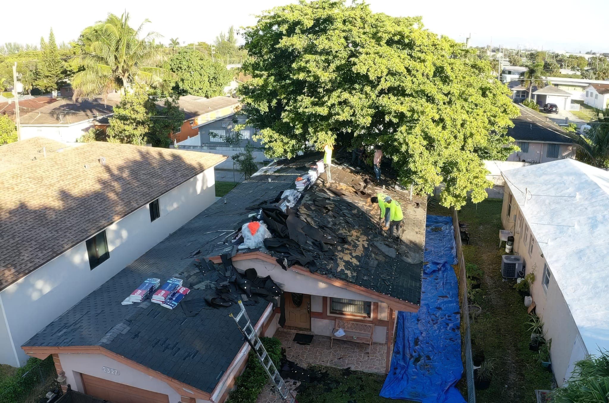 Drone view of the crew stripping the old shingle roof with the old shingles still on the far slope