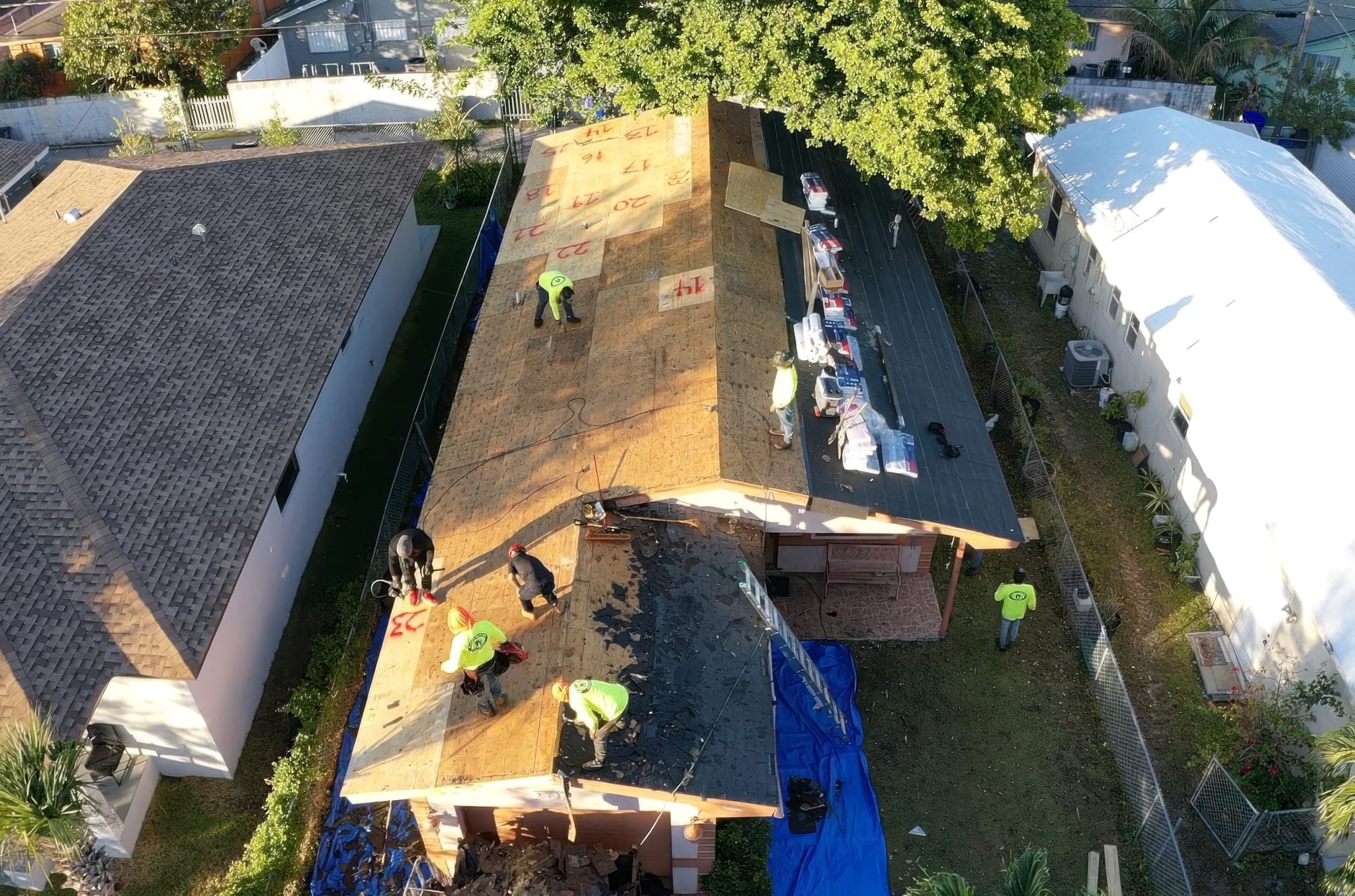 Aerial view of the roof during tear-off, bare decking exposed and new materials staged