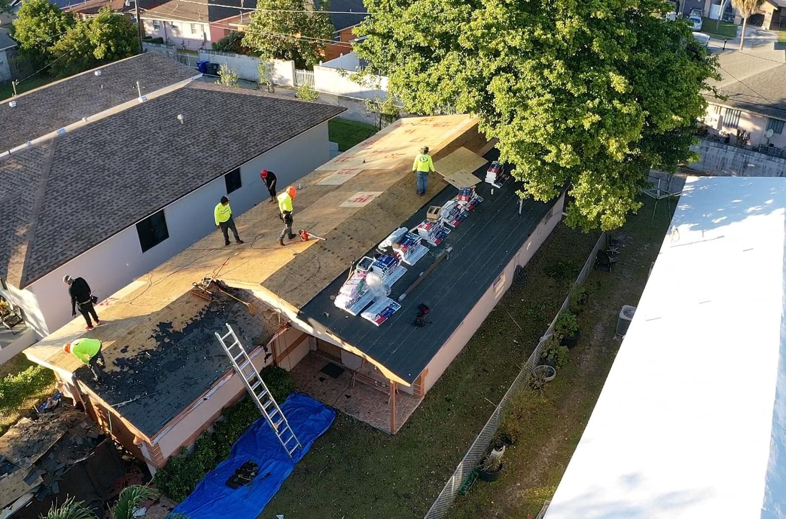 Crew in safety vests installing underlayment on the stripped roof deck