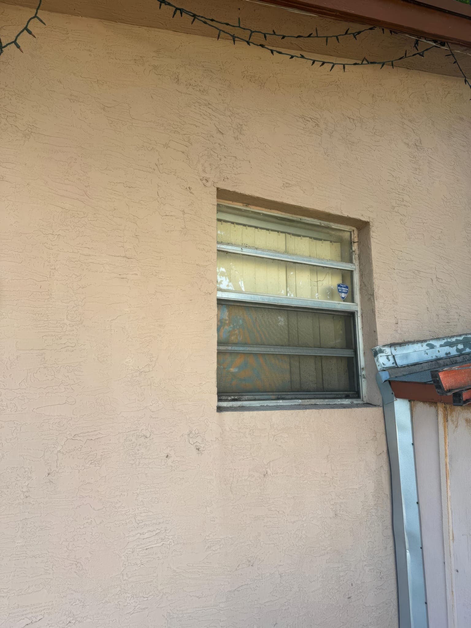 Old single-pane window at the corner of the house before replacement