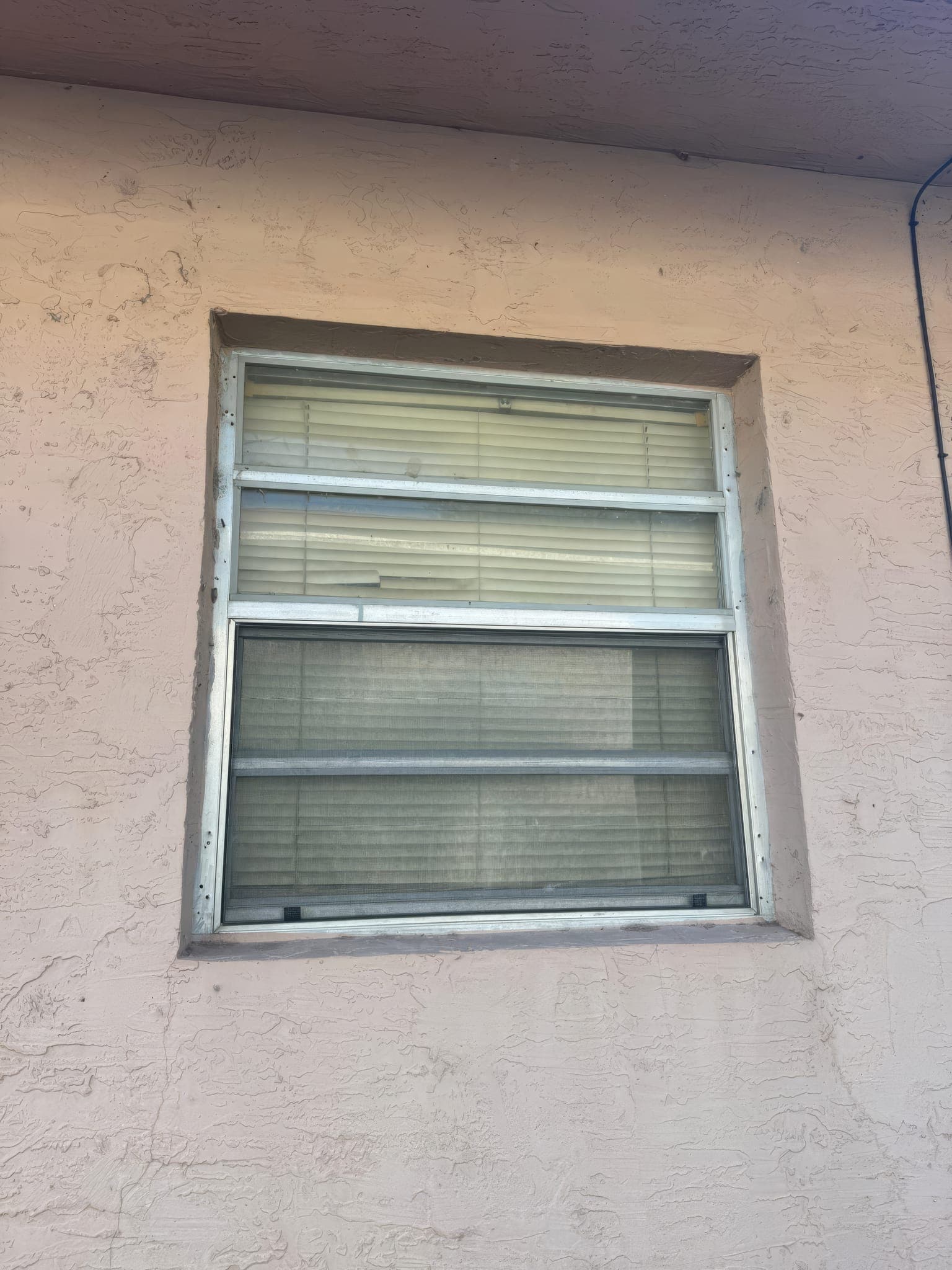 Original window with cracked stucco around the frame before replacement