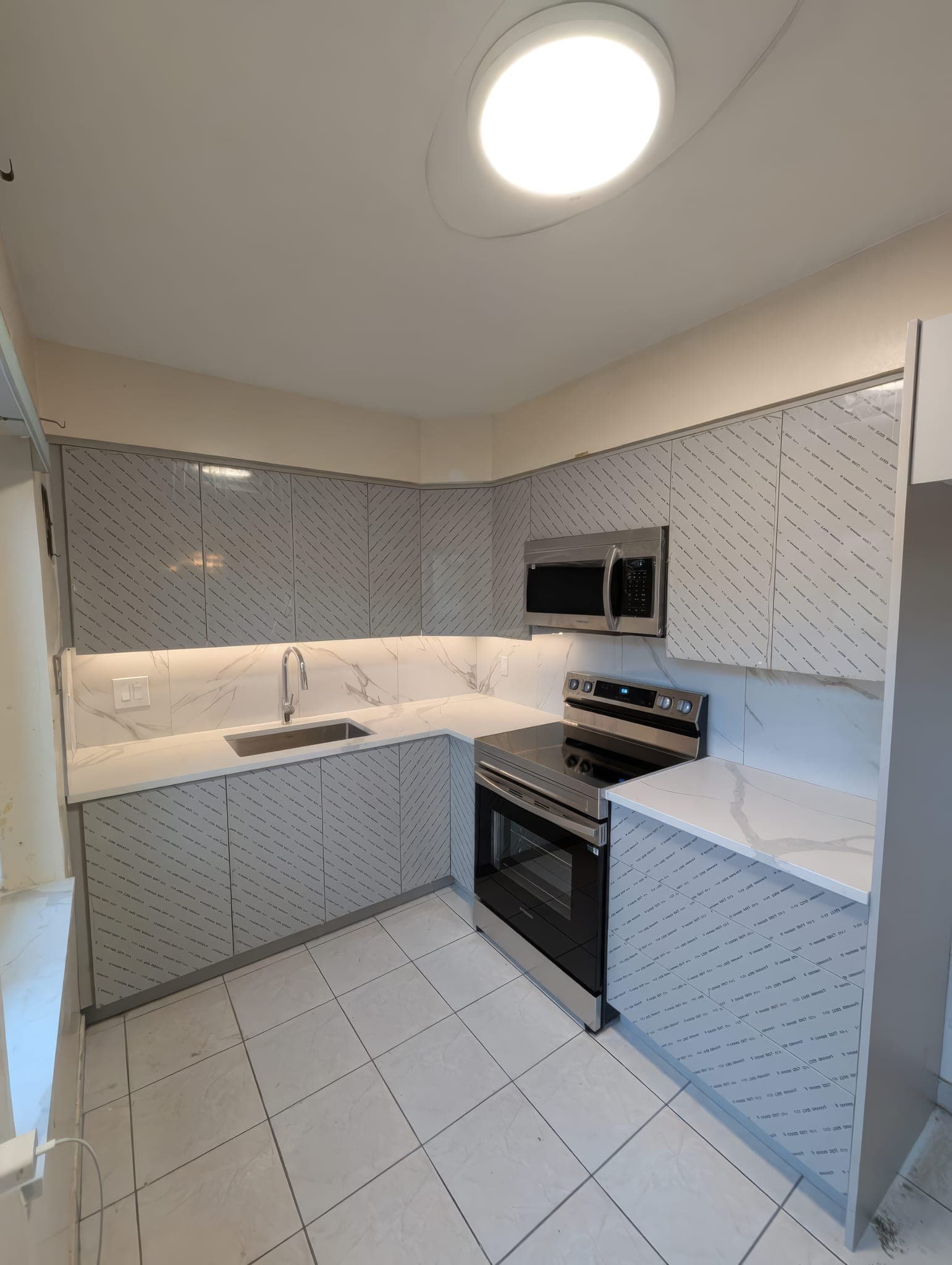 Grey gloss cabinets with marble-look backsplash and undermount sink