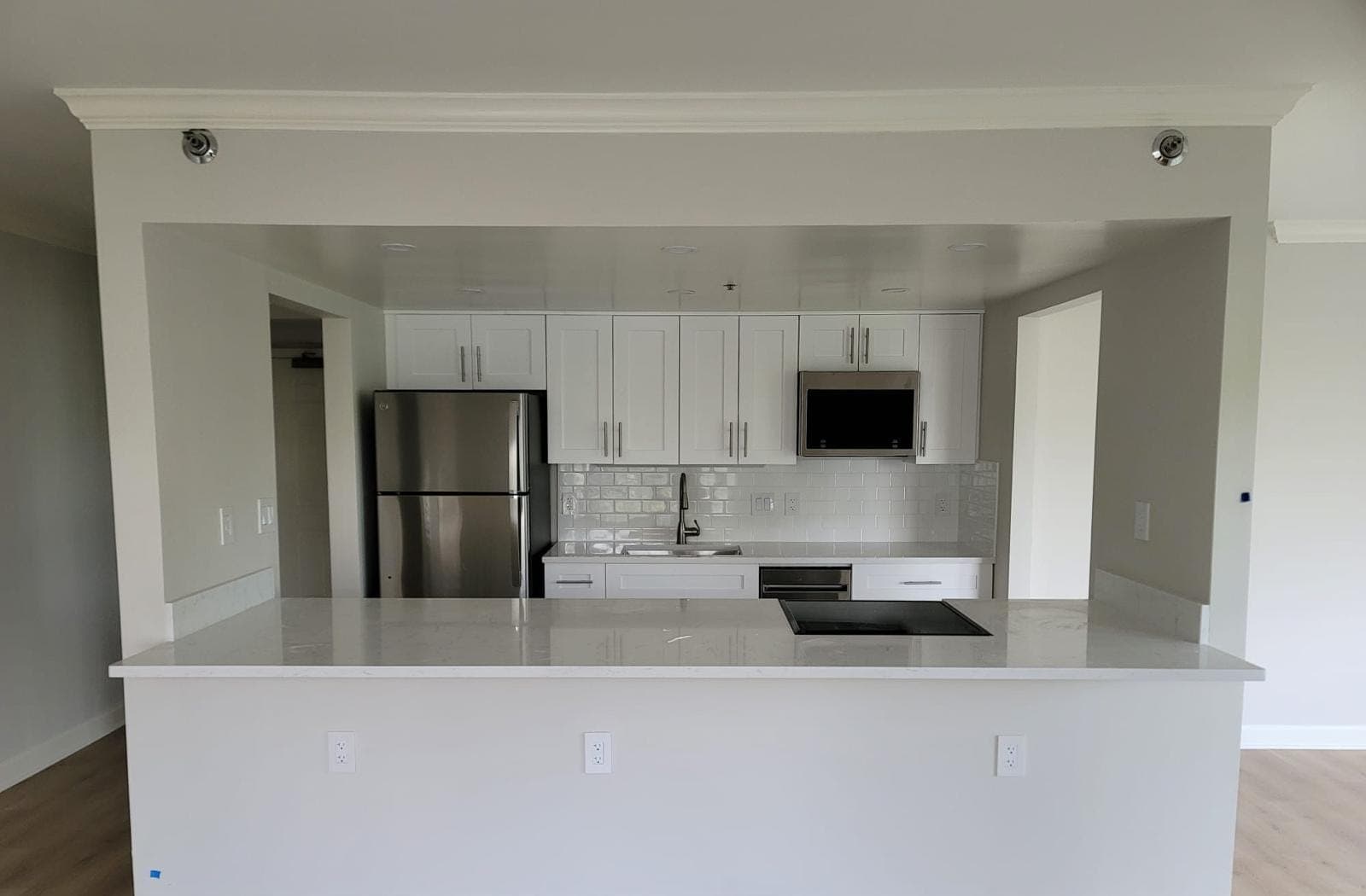 Kitchen remodeled by Sade Roofing with white shaker cabinets and quartz peninsula