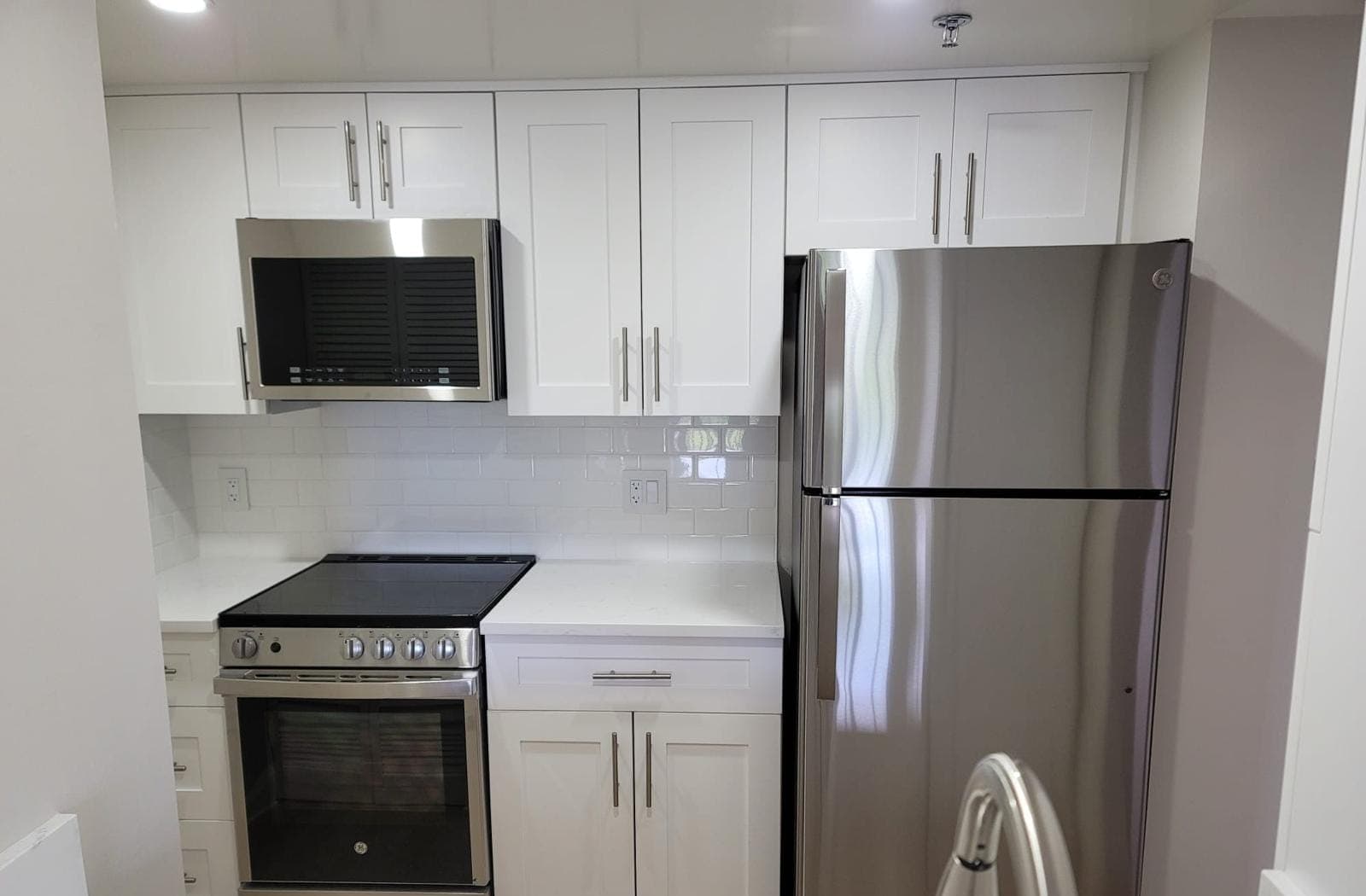 Stainless range and over-the-range microwave in a white shaker kitchen