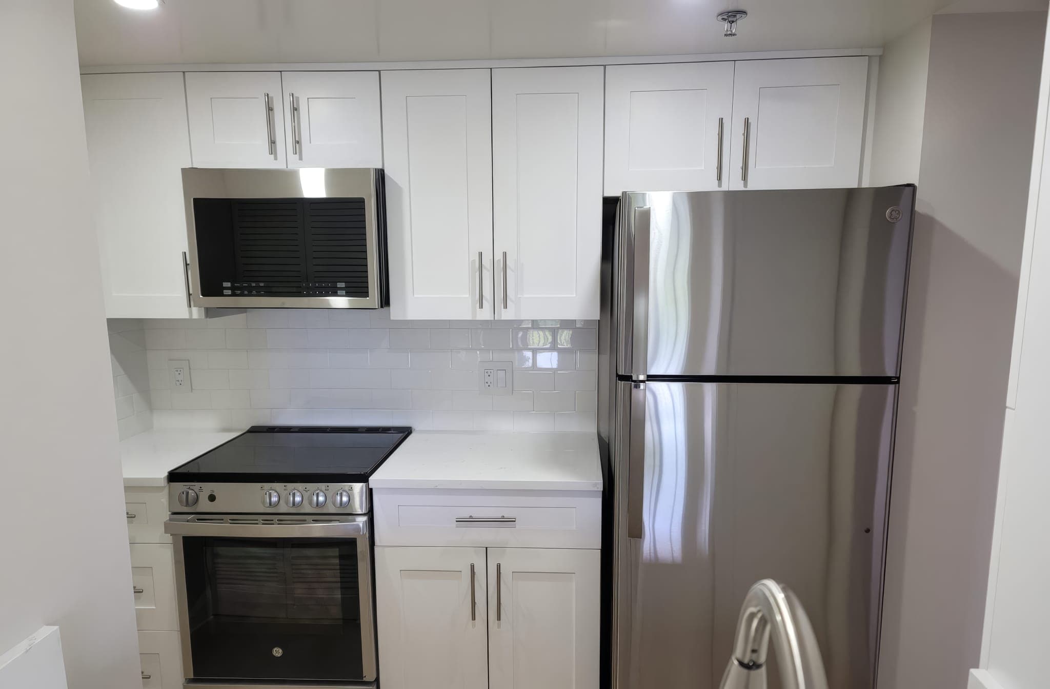 Stainless range and over-the-range microwave in a white shaker kitchen