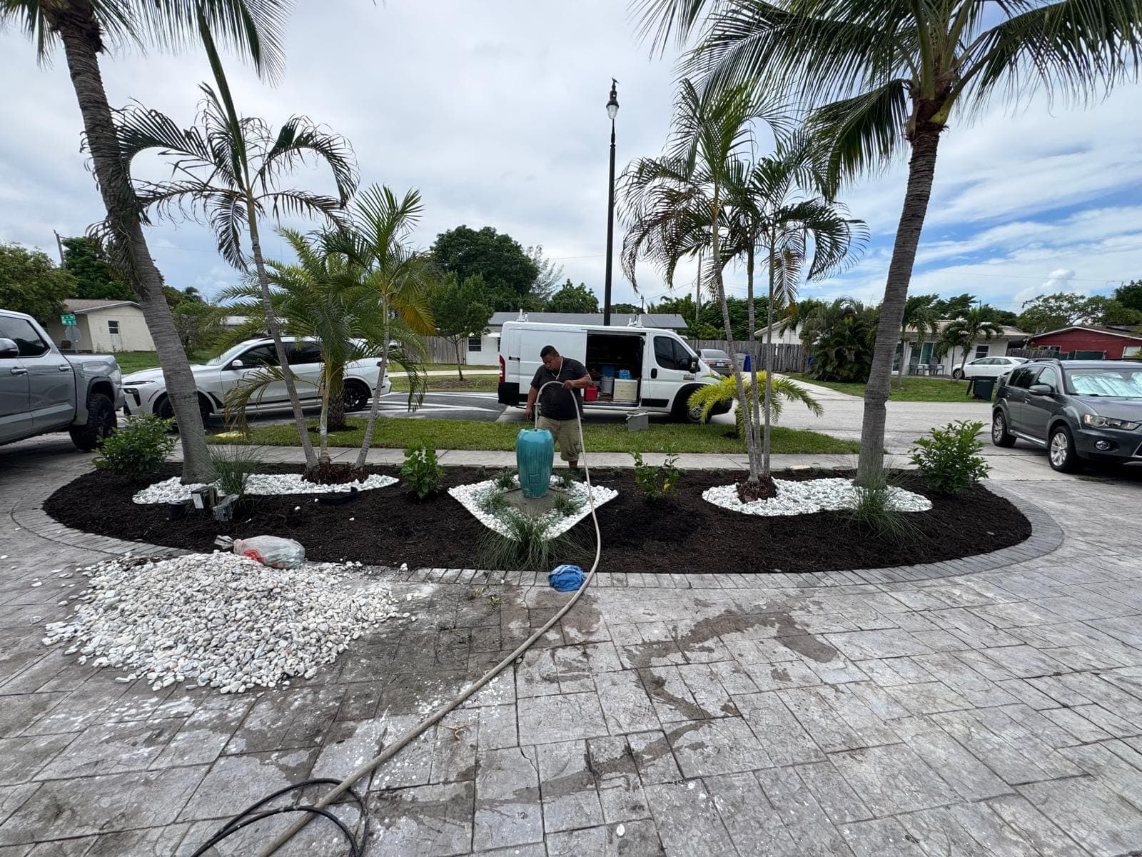 Paver driveway with new palm beds and river rock