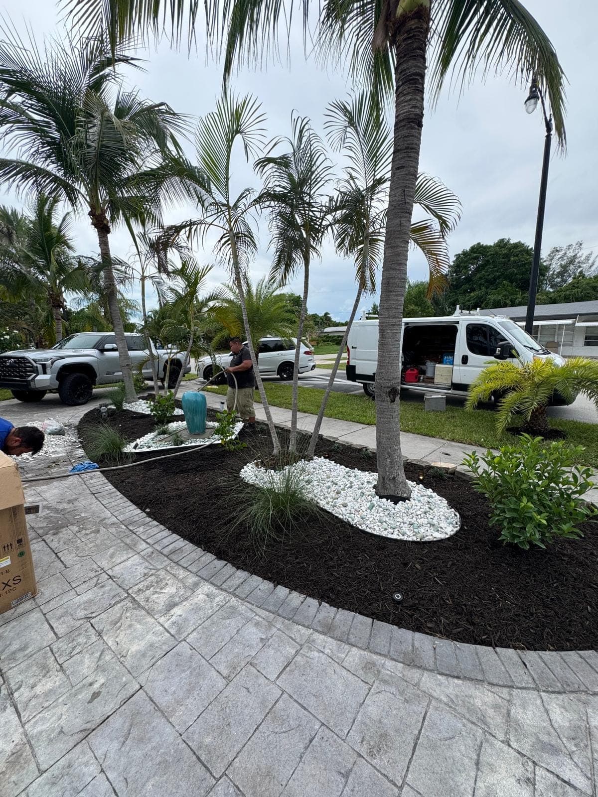 Crew setting planting beds along a paver walkway