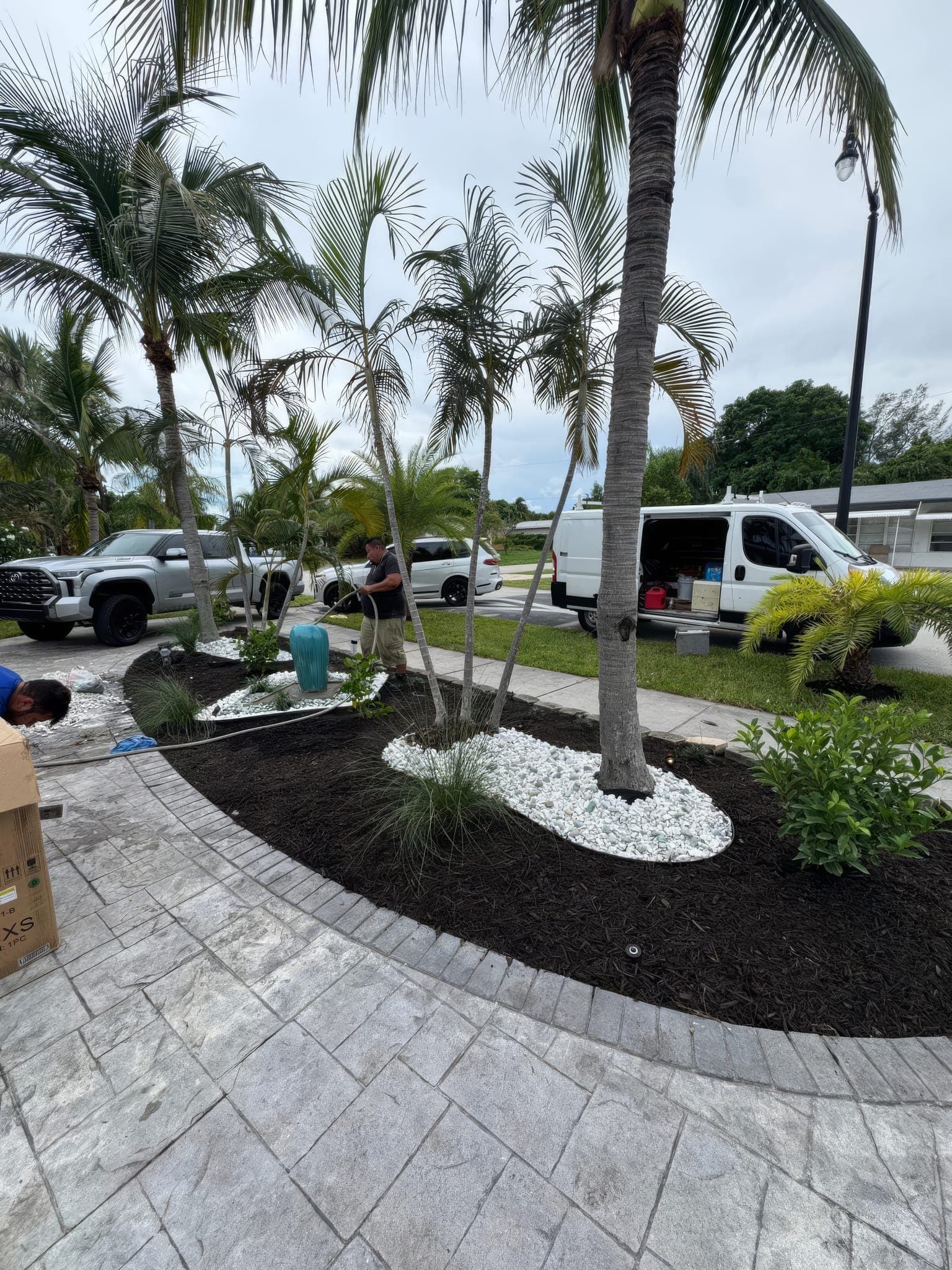 Crew setting planting beds along a paver walkway
