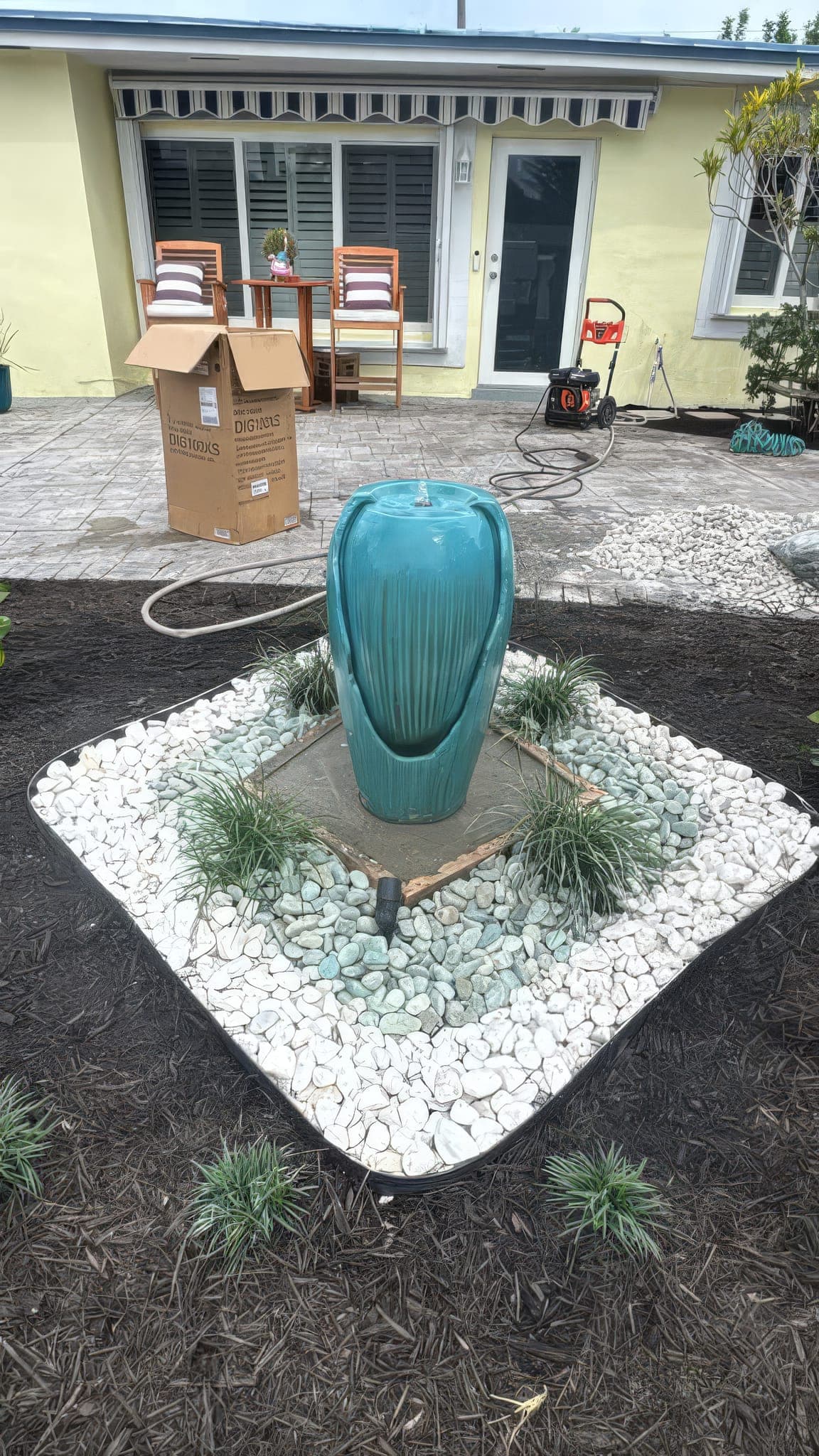 Teal glazed fountain set in river rock and grasses