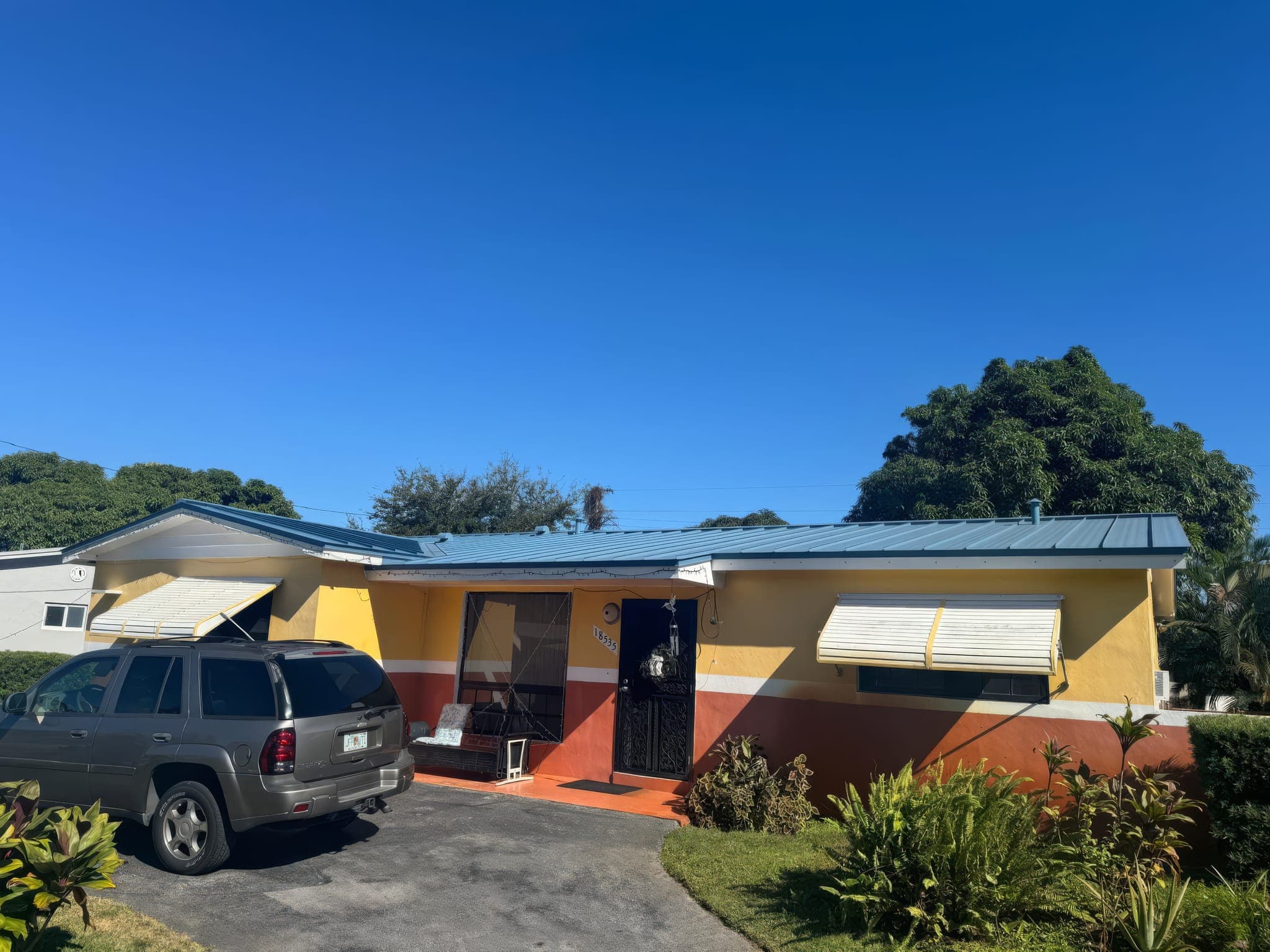 Front of a home with new metal roof, awnings and painted stucco