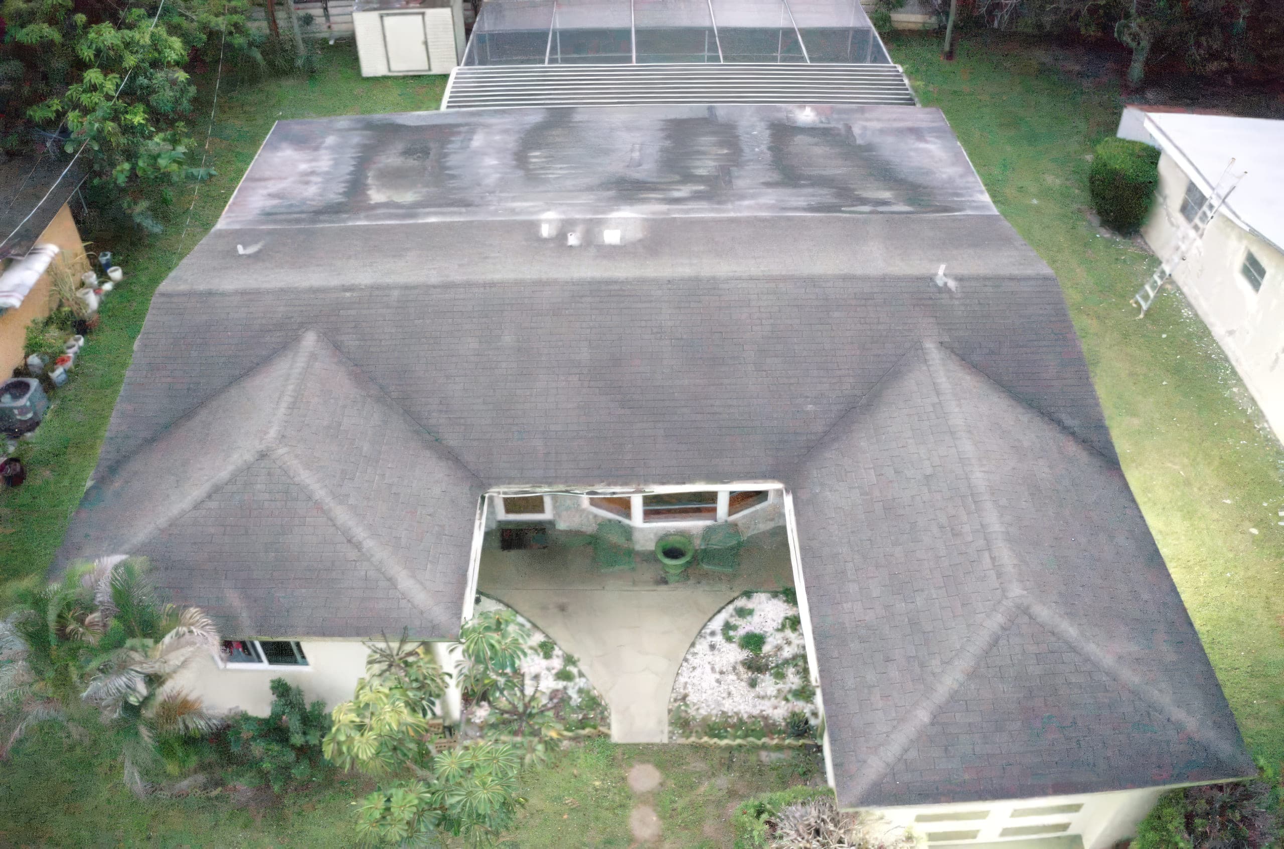 Aerial view of worn shingles and the courtyard side of the house before re-roofing
