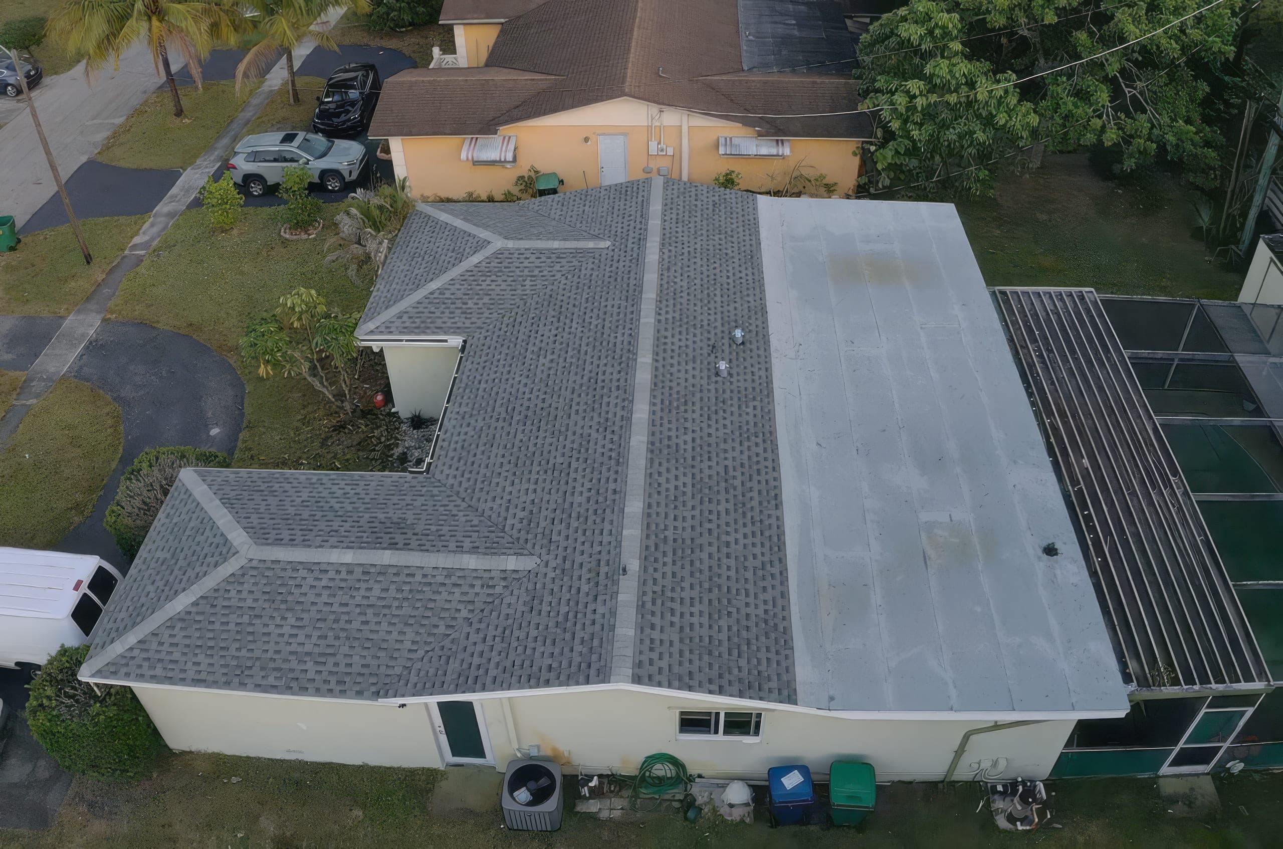 Aerial view of the completed roof: new shingles on the slopes and a new flat roof over the rear