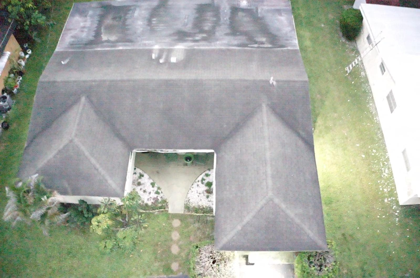 Overhead drone view of a shingle roof and screened patio
