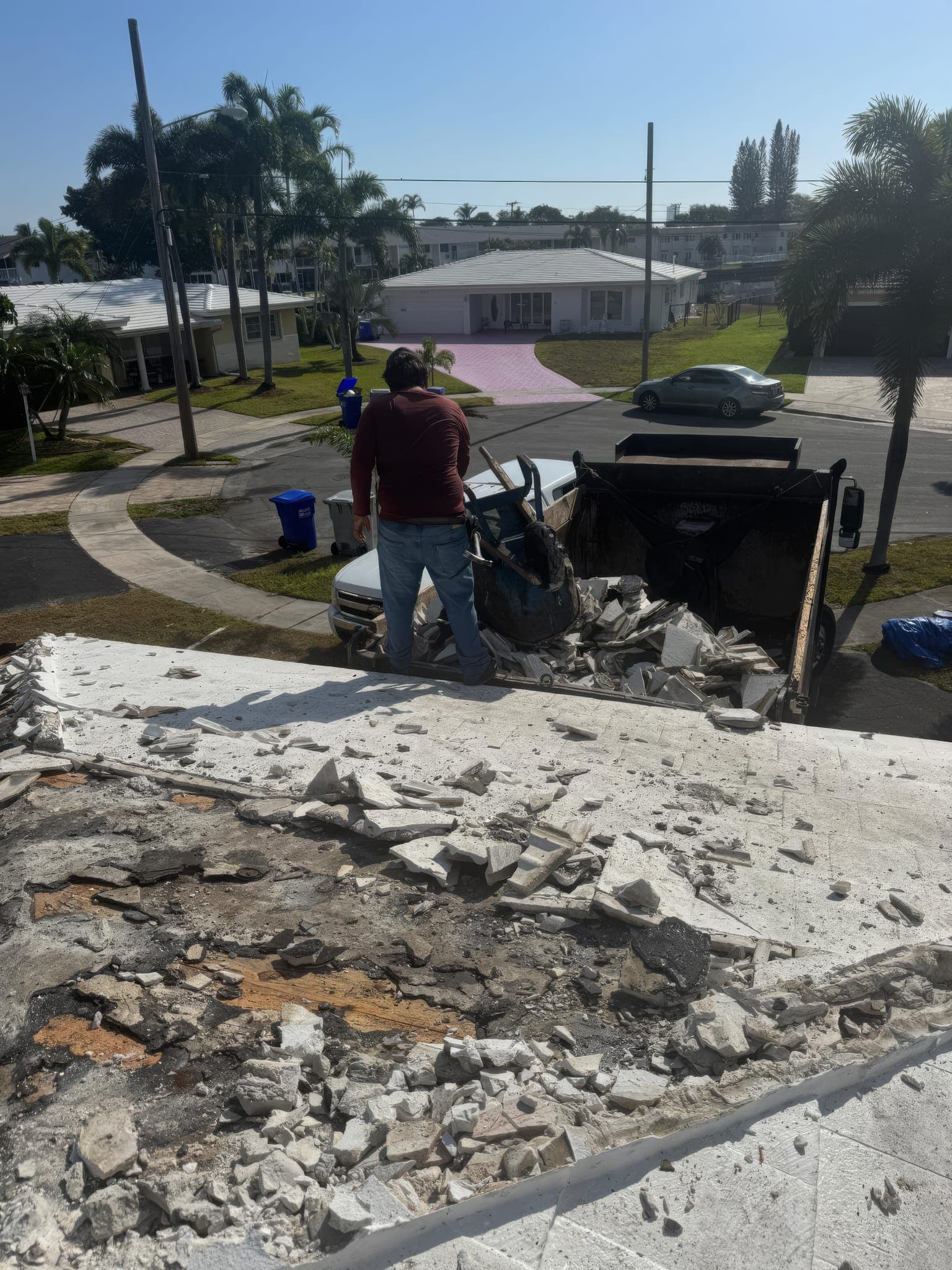 Roof debris being cleared off the edge into the trailer below