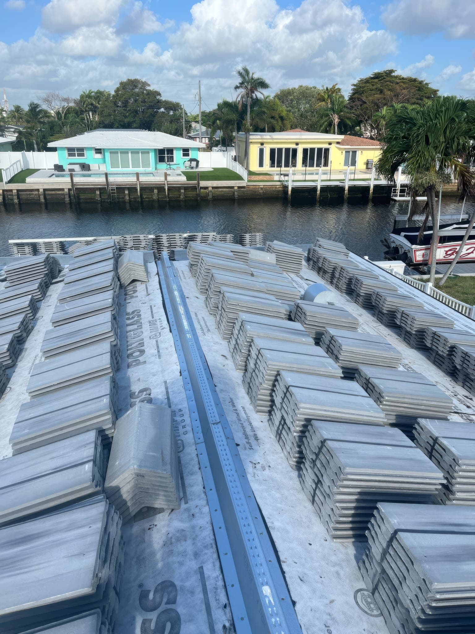 Bundles of white flat concrete tile staged on the roof above the canal