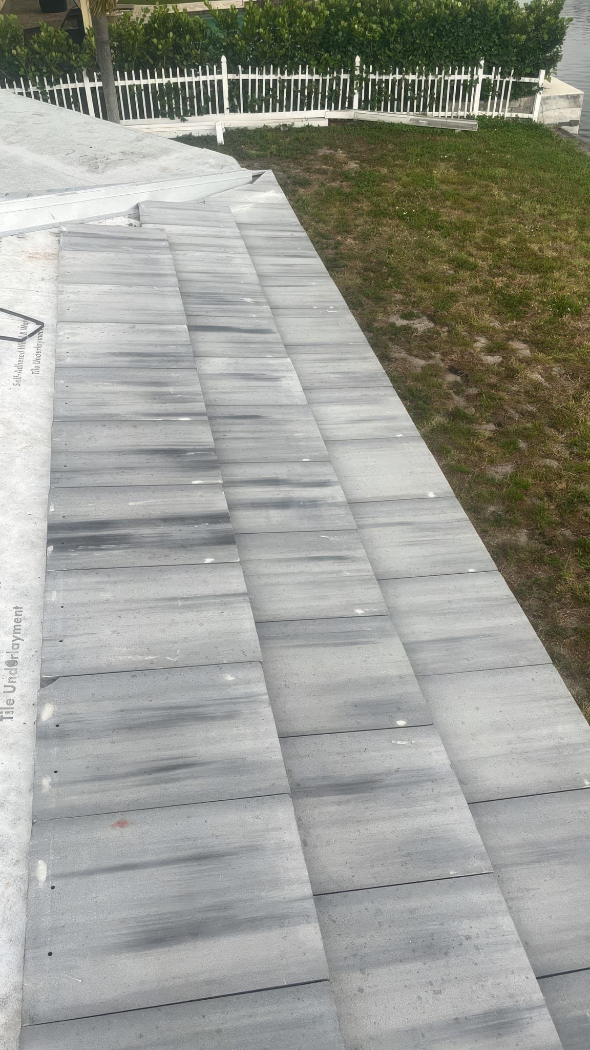 First courses of white flat tile set along the eave of the canal-front home