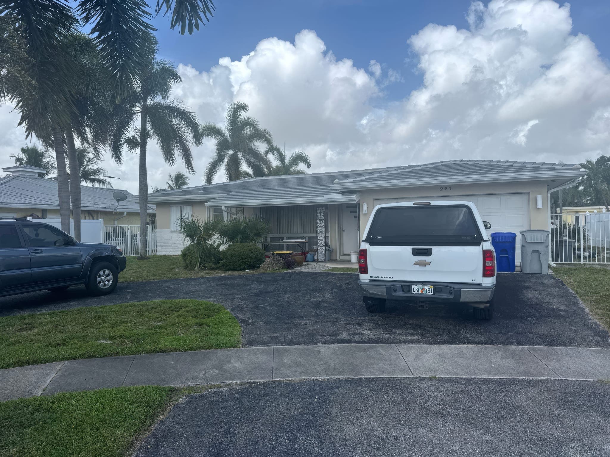 Completed white tile roof from the driveway, palms in front and the canal behind