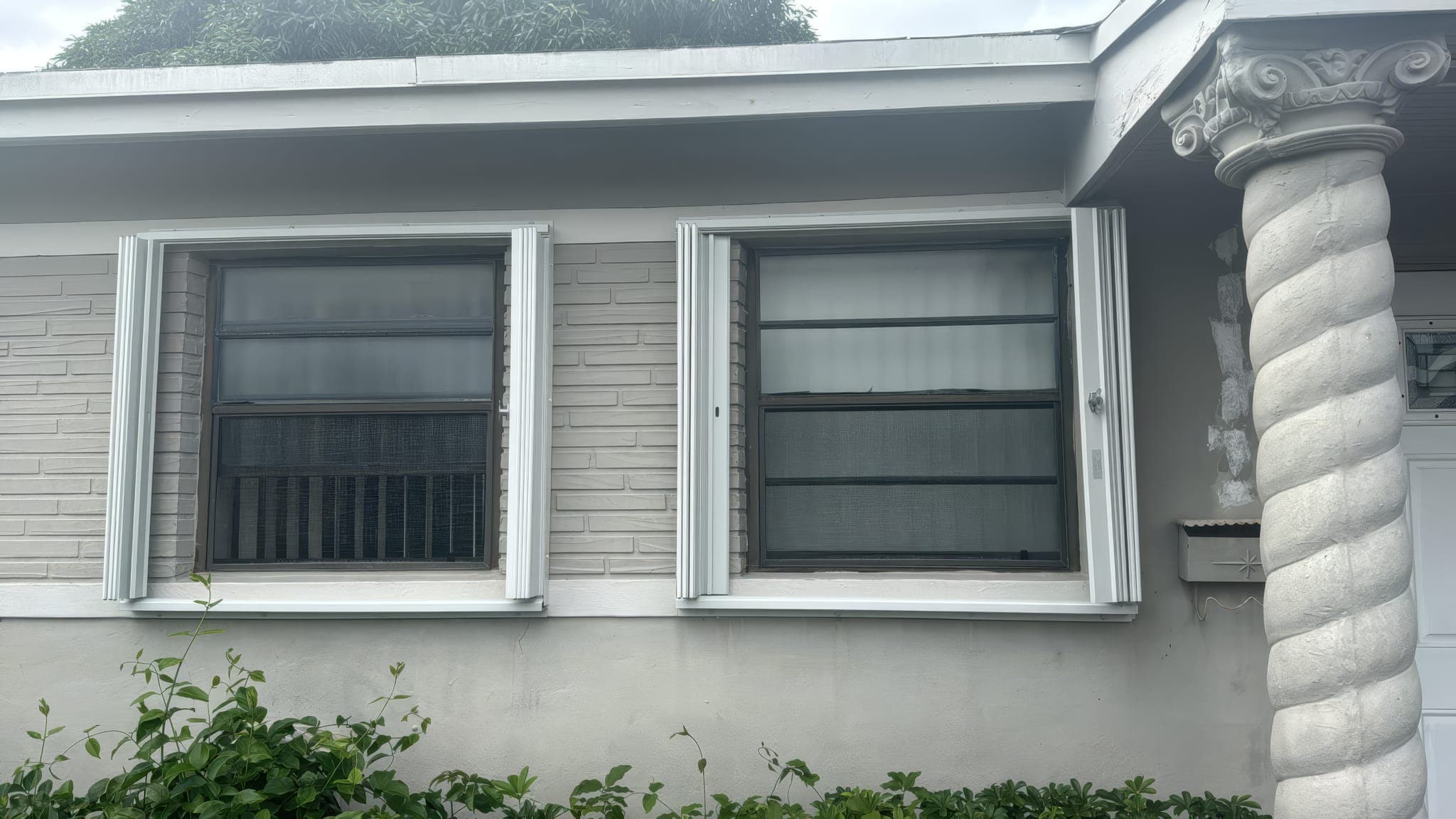 Two original single-pane windows on a stucco wall before replacement