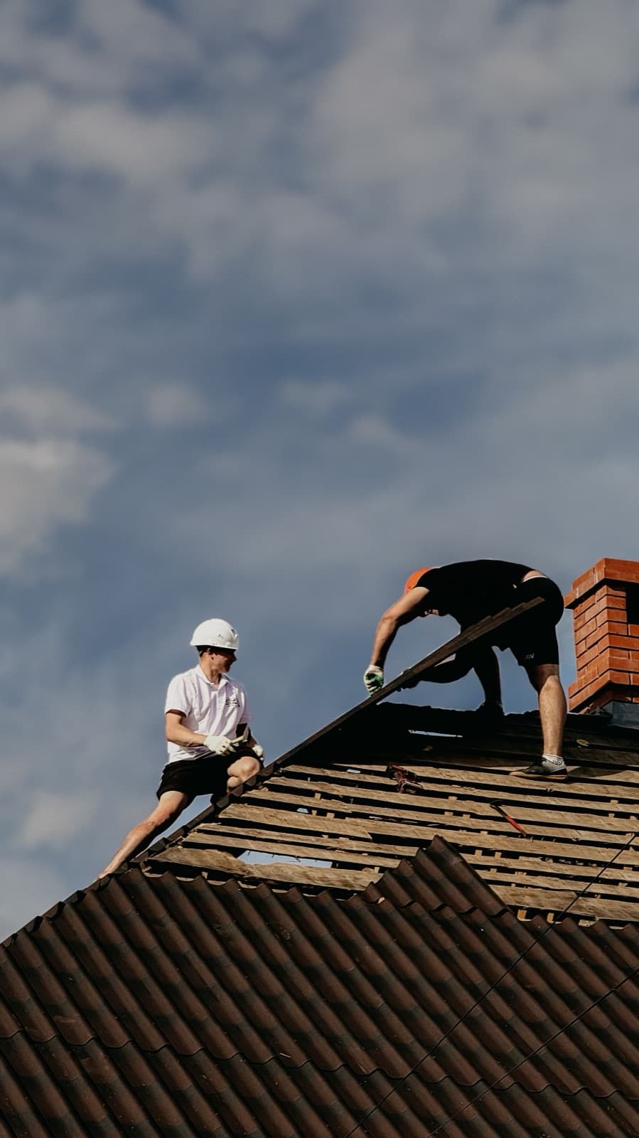 Roofers setting tile on a sloped roof